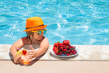 Wall Mural - Child in swimming pool playing in summer water. Vacation and traveling with kids. Summer fruits for children.