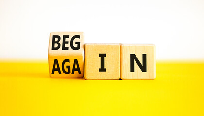 Wall Mural - Begin again symbol. Businessman turns wooden cubes and changes the word begin to again. Beautiful yellow table white background. Business and begin again concept. Copy space.