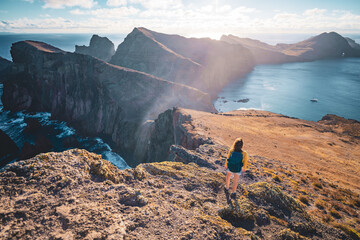 Wall Mural - Back view of a backpacker woman enjoing view over the foothills of an island in the Atlantic Ocean. São Lourenço, Madeira Island, Portugal, Europe.