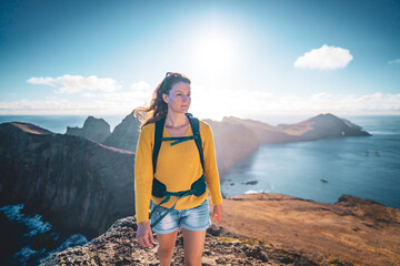 Wall Mural - Front view of a tourist backpacker standing on top of foothills of an island in the Atlantic Ocean in the morning. São Lourenço, Madeira Island, Portugal, Europe.