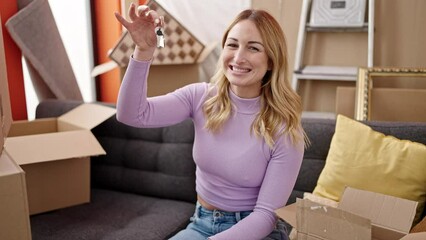 Sticker - Young beautiful hispanic woman holding keys sitting on sofa at new home