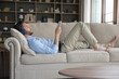© fizkes - Peaceful millennial young man in big wireless headphones relaxing on comfortable sofa, listening to ambient music for meditation, using playlist on Internet, enjoying silent leisure, break at home