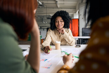 Wall Mural - Portrait of beautiful smiling African American business woman  talking, planning startup, sharing ideas working together with colleagues in modern office. Meeting, teamwork, successful business