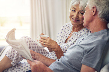 Coffee, newspaper and a senior couple in the bedroom, enjoying retirement in their home in the morning. Tea, reading or love with a happy mature man and woman in bed together to relax while bonding