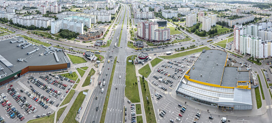 Wall Mural - aerial panoramic view of city residential area with high-rise apartment houses, and supermarkets with parking lots, wide streets with road intersections