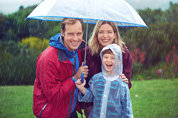 Canvas Print - Happy family, child and portrait in rain with umbrella in nature outdoor for fun, happiness and quality time. Man, woman and boy kid laughing for water drops or freedom while playing in winter