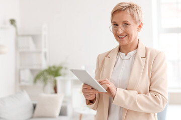 Mature psychologist working with tablet computer in office