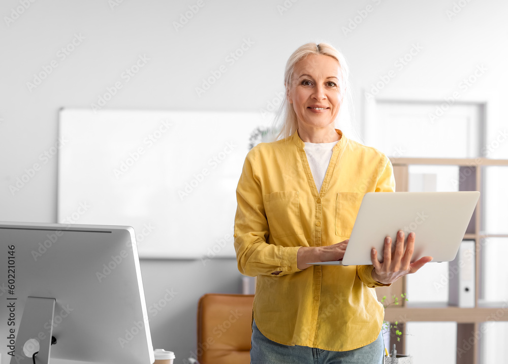 Mature female programmer working with laptop in office