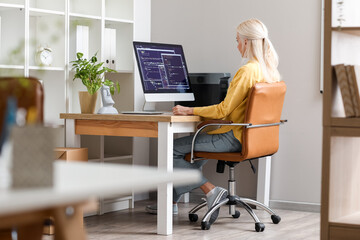 Sticker - Mature female programmer working with computer at table in office