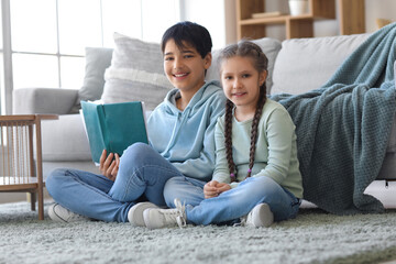 Wall Mural - Little boy with his sister reading story at home