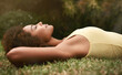 © Mapodile M/peopleimages.com - Dreaming, grass and mockup with a black woman lying on a field for peace or quiet in nature during the day. Sleeping, relax and zen with an attractive young female resting alone in the countryside