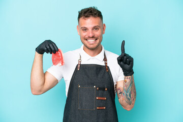 Wall Mural - Butcher caucasian man wearing an apron and serving fresh cut meat isolated on blue background pointing up a great idea