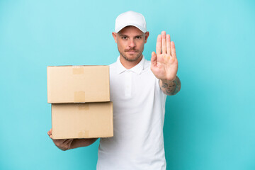 Wall Mural - Delivery caucasian man isolated on blue background making stop gesture