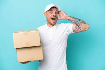 Delivery caucasian man isolated on blue background with surprise expression