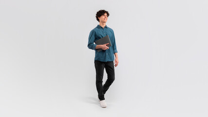 Cheerful Young Man Holding Laptop Computer Standing In Studio