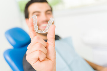 Wall Mural - Smiling young man using invisible orthodontics