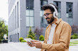 © Liubomir - A young Inus man walks around the city in headphones, a businessman in a shirt watches an online video stream using a tablet computer, a programmer in a shirt outside an office building.