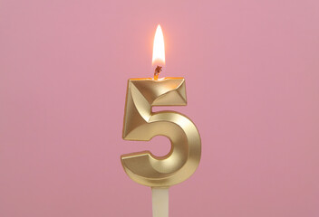 Golden birthday candle burning on pink background, number 5.