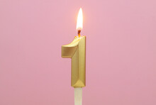 Golden Birthday Candle Burning On Pink Background, Number 1.
