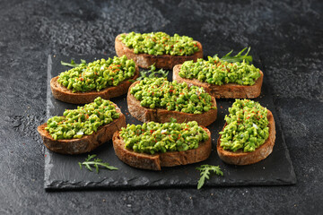 Wall Mural - Mashed peas sourdough bread toast with sea salt flakes and chilli served on black slate