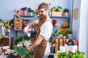 Wall Mural - Young redhead man florist using difusser working at flower shop