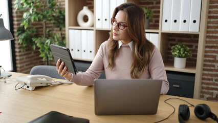 Poster - Young beautiful hispanic woman business worker using touchpad and laptop at office