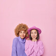 © wayhome.studio  - Vertical shot of two thoughtful women have dreamy expressions concentrated above dressed in casual knitted jumpers and elegant hat isolated on pink background empty space for your advertising content