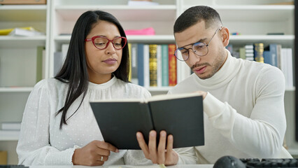 Man and woman students reading book studying at university classroom