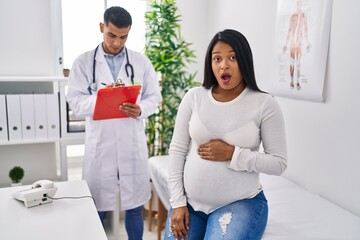 Canvas Print - Young hispanic mother expecting a baby at the doctor scared and amazed with open mouth for surprise, disbelief face