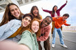 © CarlosBarquero - Group of happy multiracial friends taking a selfie photo with cell phone outside. Happy young people together smiling at camera. Youth concept with boys and girls having fun walking along city street.