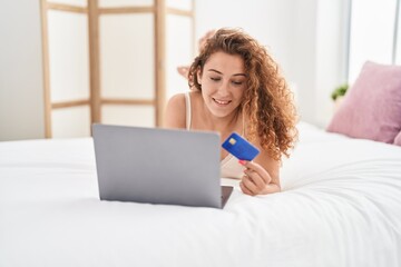 Wall Mural - Young beautiful hispanic woman using laptop and credit card sitting on bed at bedroom