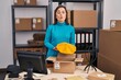 Middle age hispanic woman working at small business ecommerce preparing order making fish face with mouth and squinting eyes, crazy and comical.