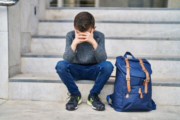 Poster - Blond child student with worried expression sitting on stairs at school