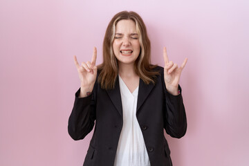 Poster - Young caucasian business woman wearing black jacket shouting with crazy expression doing rock symbol with hands up. music star. heavy music concept.