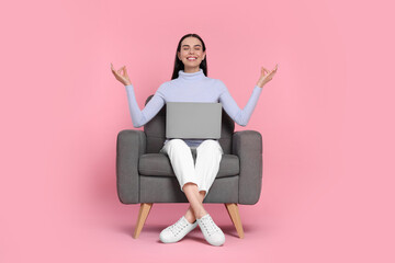 Canvas Print - Happy woman with laptop sitting in armchair and meditating on pink background