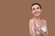 © New Africa - Beautiful woman with smear of body cream on her arm against light brown background, space for text