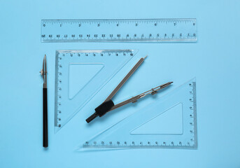 Wall Mural - Different rulers and compass on light blue background, flat lay