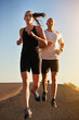 © Nicola K/peopleimages.com - Sunrise, marathon and friends running as workout or morning exercise for health and wellness together. Sport, man and woman runner run with athlete as training, sports or energy on a road