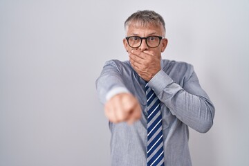 Sticker - Hispanic business man with grey hair wearing glasses laughing at you, pointing finger to the camera with hand over mouth, shame expression