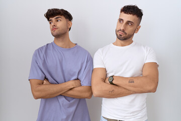 Poster - Homosexual gay couple standing over white background looking to the side with arms crossed convinced and confident