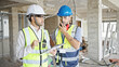 © Krakenimages.com - Two men builders talking on walkie talkie reading document at construction site