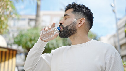 Sticker - Young hispanic man drinking water at park