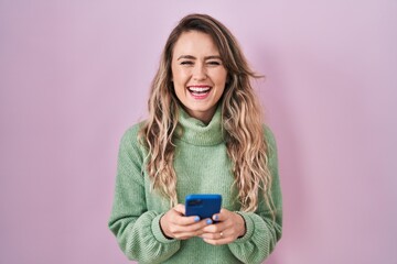 Poster - Young caucasian woman using smartphone typing message smiling and laughing hard out loud because funny crazy joke.