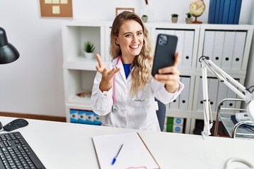 Wall Mural - Young woman wearing doctor uniform having telemedicine at clinic