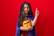 Little Hispanic Girl Wearing Witch Halloween Costume Smiling Happy Pointing With Hand And Finger To The Side