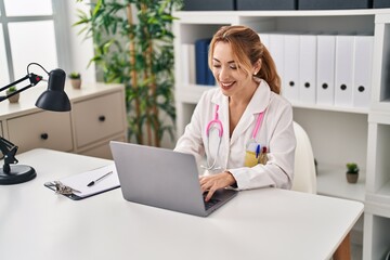 Wall Mural - Young woman wearing doctor uniform using laptop working at clinic