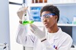 © Krakenimages.com - African american woman wearing scientist uniform measuring liquid at laboratory