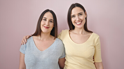 Poster - Two women smiling confident hugging each other over isolated pink background