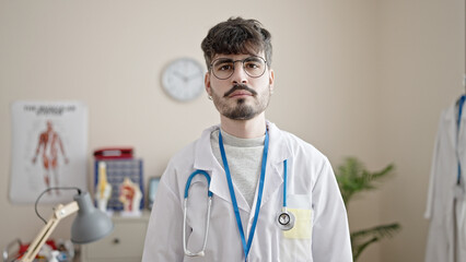 Poster - Young hispanic man doctor standing with serious expression at clinic