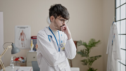 Poster - Young hispanic man doctor standing with serious expression at clinic